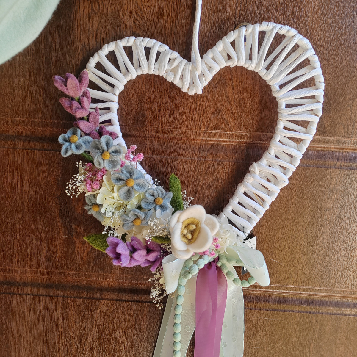 Cuore con fiori in lana e nastri cadenti